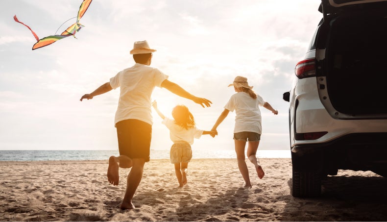 Family running on the beach towards the water